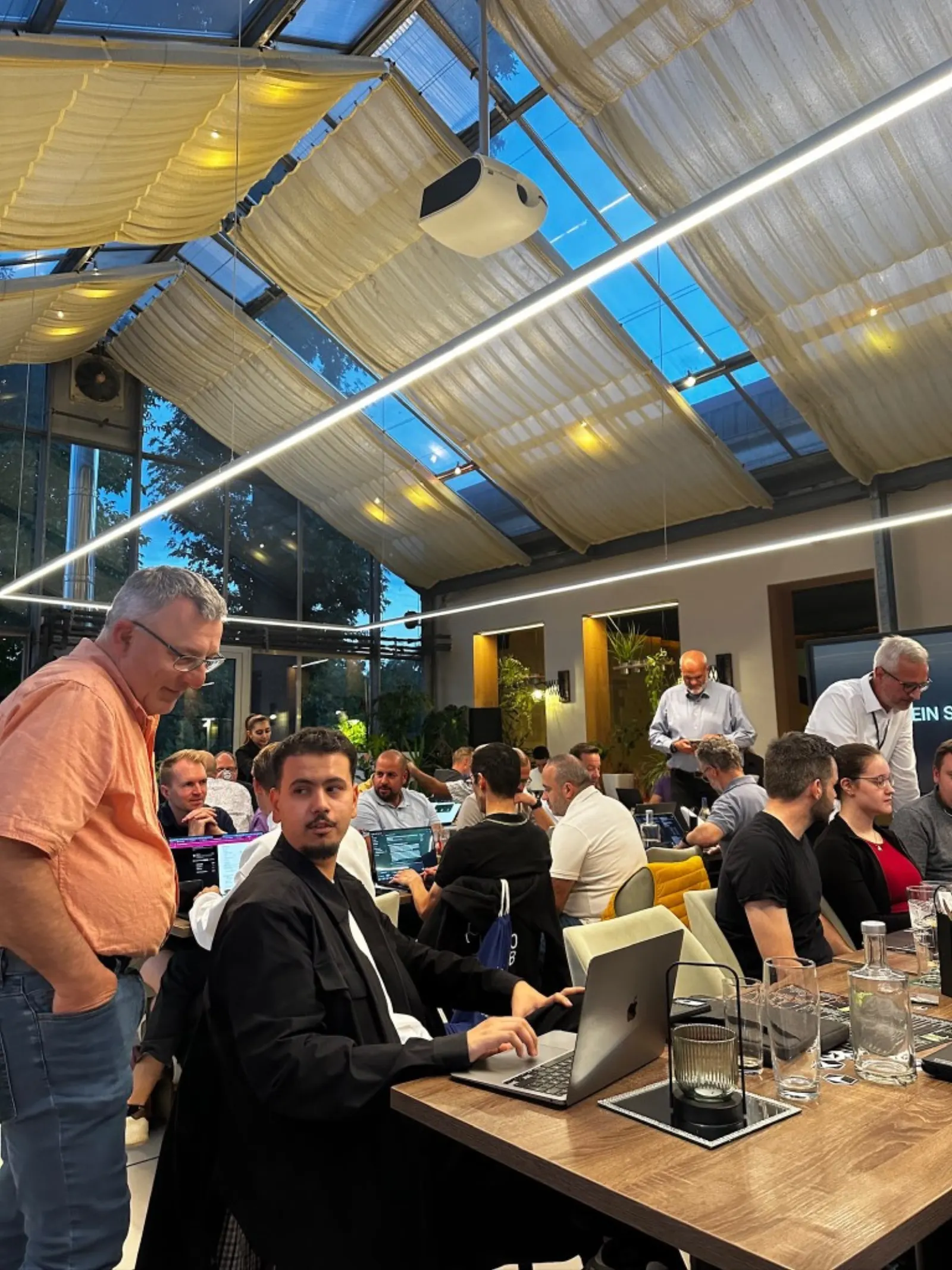 Cursor Kassel Build Day, Workshop unter dem Glasdach mit Laptops auf den Tischen